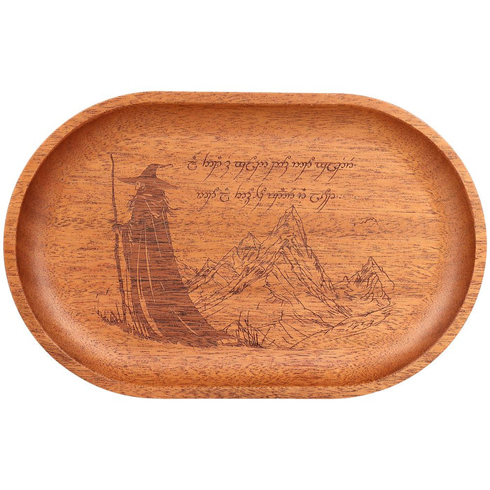 An oval wooden tray with a warm medium-brown finish, featuring an engraved illustration of a wizard holding a staff and mountains, with Elvish script text on the top right.