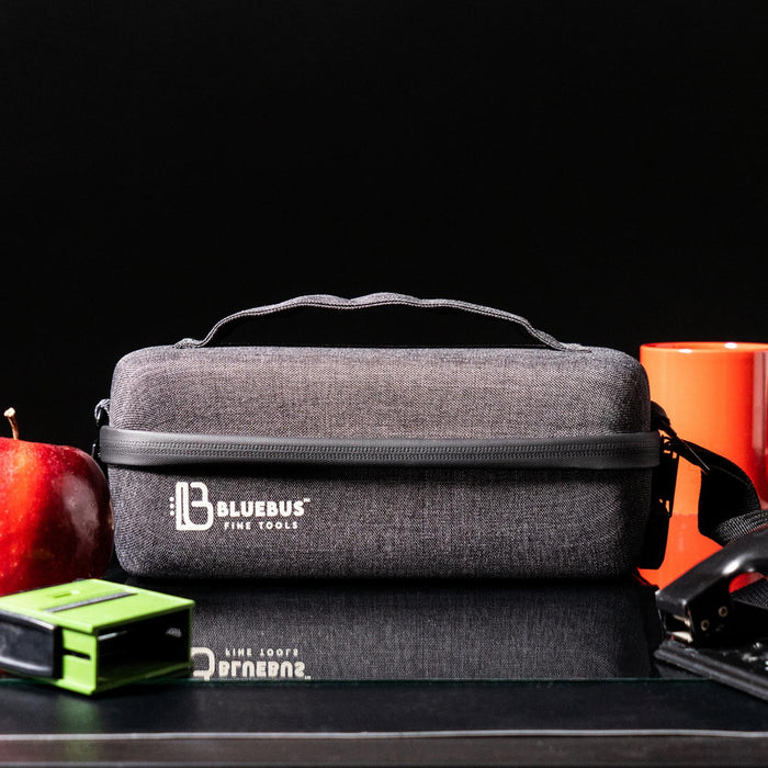 Gray carrying case with Bluebus logo on a reflective surface with an apple and other items.