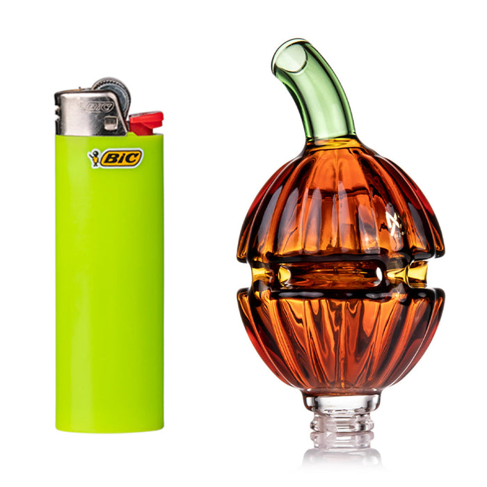 Green BIC lighter next to a glass pumpkin-shaped bottle on a white background