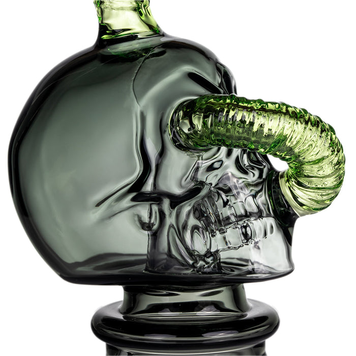 Glass skull decanter with green accents on a white background