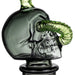 Glass skull decanter with green accents on a white background