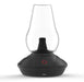 Black and glass lamp-like device on a white background